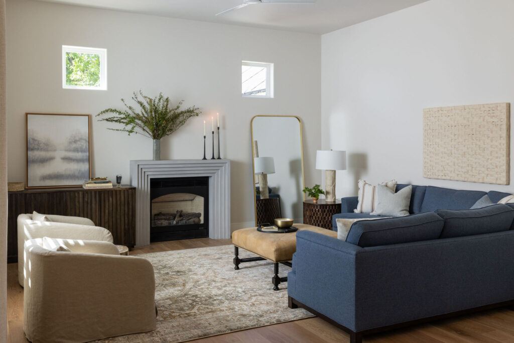 Interior designed living room with neutral wall color, square windowns, blue couch with neutral color pillow and brown rug in Sacramento CA