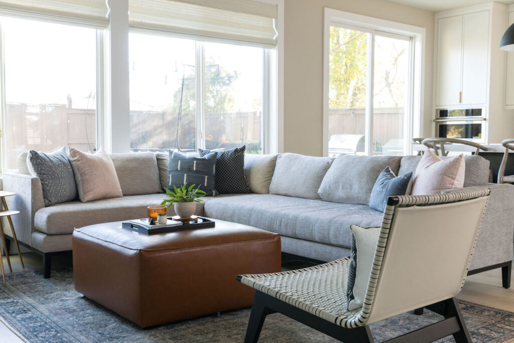 Living room with neutral paint, blue wraparound couch and brown ottoman interior design Placer County CA